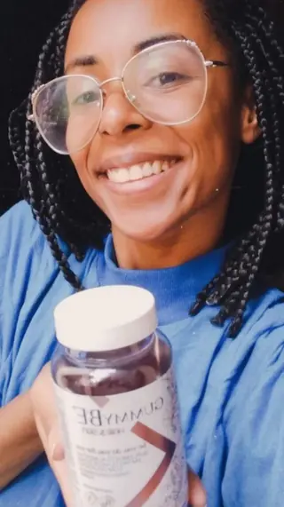 Cliente de tranças sorrindo com o pote de GummyBe