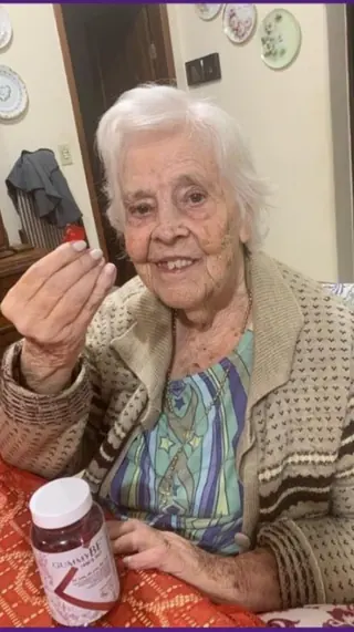 Senhora sorrindo com uma gominha e o pote de GummyBe